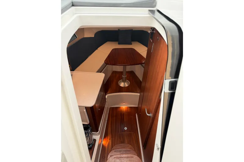  Yacht Photos Pics 2025 Pursuit OS 325 Offshore cabin interior with wood finishes and seating area.
