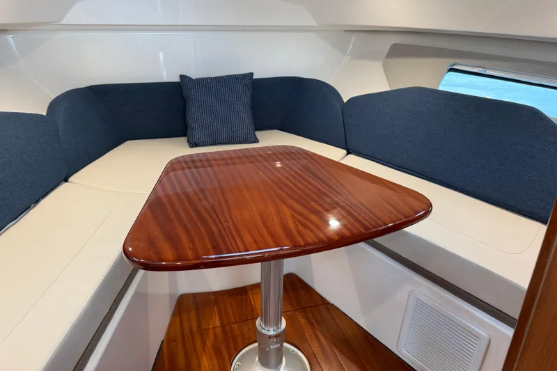  Yacht Photos Pics 2025 Pursuit OS 325 Offshore cabin with wooden table and blue seating.