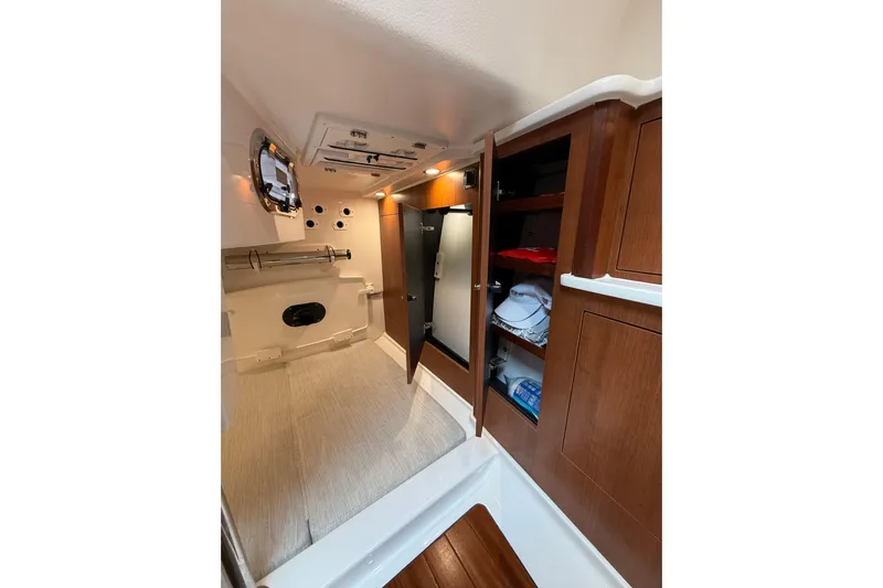  Yacht Photos Pics 2025 Pursuit OS 325 Offshore cabin interior with wood cabinetry and storage.
