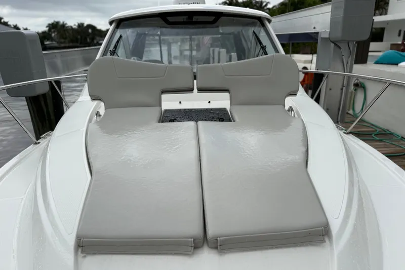  Yacht Photos Pics 2025 Pursuit OS 325 Offshore boat with cushioned deck seating, docked by the water.