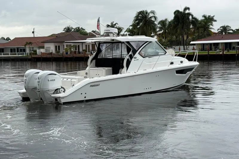  Yacht Photos Pics 2025 Pursuit OS 325 Offshore boat on calm water, surrounded by waterfront homes.