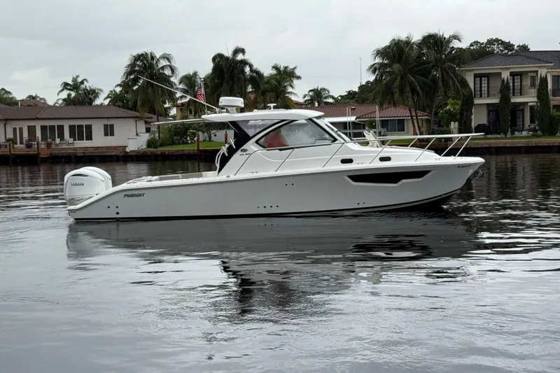  Yacht Photos Pics 2025 Pursuit OS 325 Offshore boat on calm water near waterfront homes.