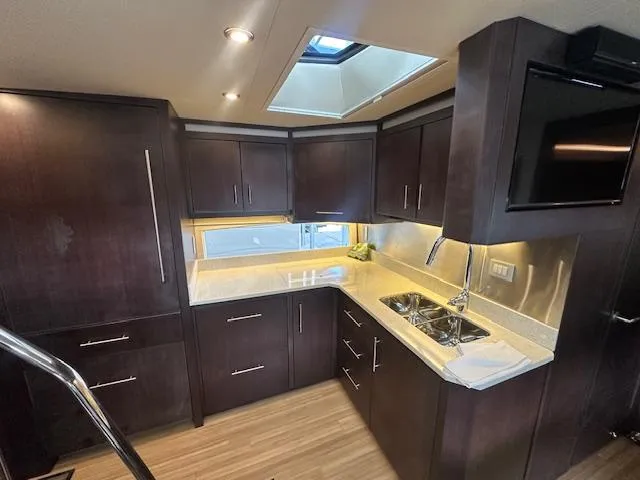  Yacht Photos Pics Luxurious kitchen interior of 2017 Regal 53 Sport Coupe yacht with dark wood cabinetry.