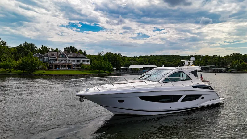  Yacht Photos Pics 2017 Regal 53 Sport Coupe yacht cruising on a scenic lake with houses in the background.