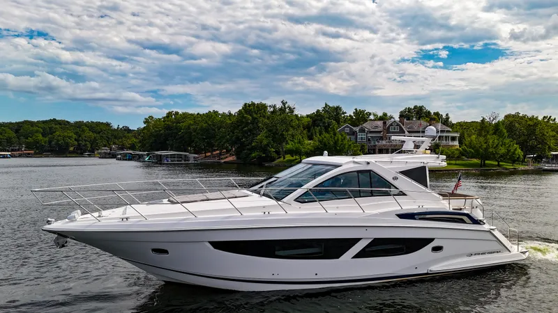  Yacht Photos Pics 2017 Regal 53 Sport Coupe yacht cruising on a scenic lake under a partly cloudy sky.