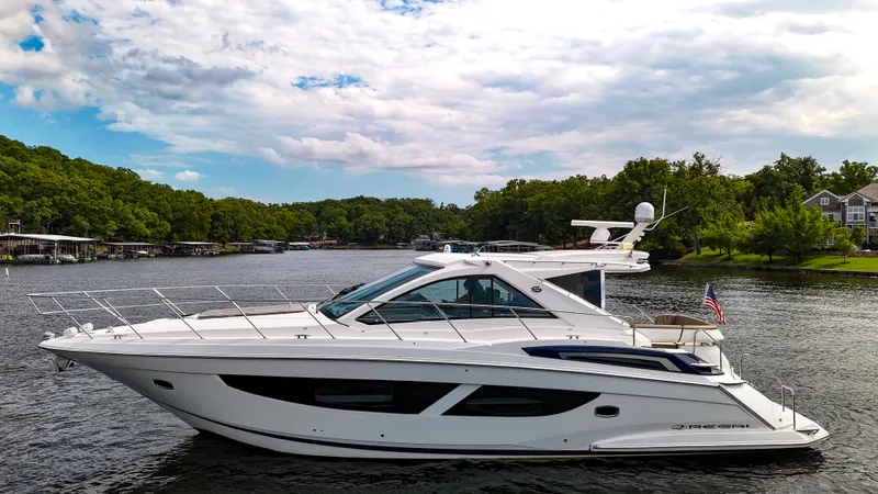  Yacht Photos Pics 2017 Regal 53 Sport Coupe yacht on a serene lake with lush green surroundings.