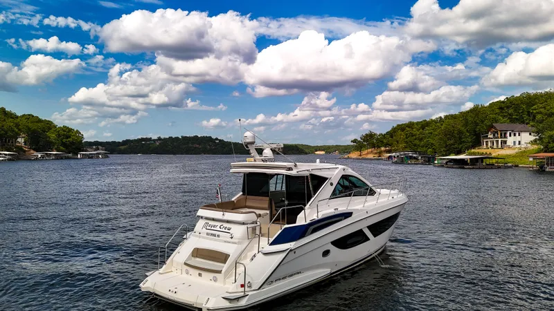  Yacht Photos Pics 2017 Regal 53 Sport Coupe yacht on a scenic lake under a blue sky with clouds.