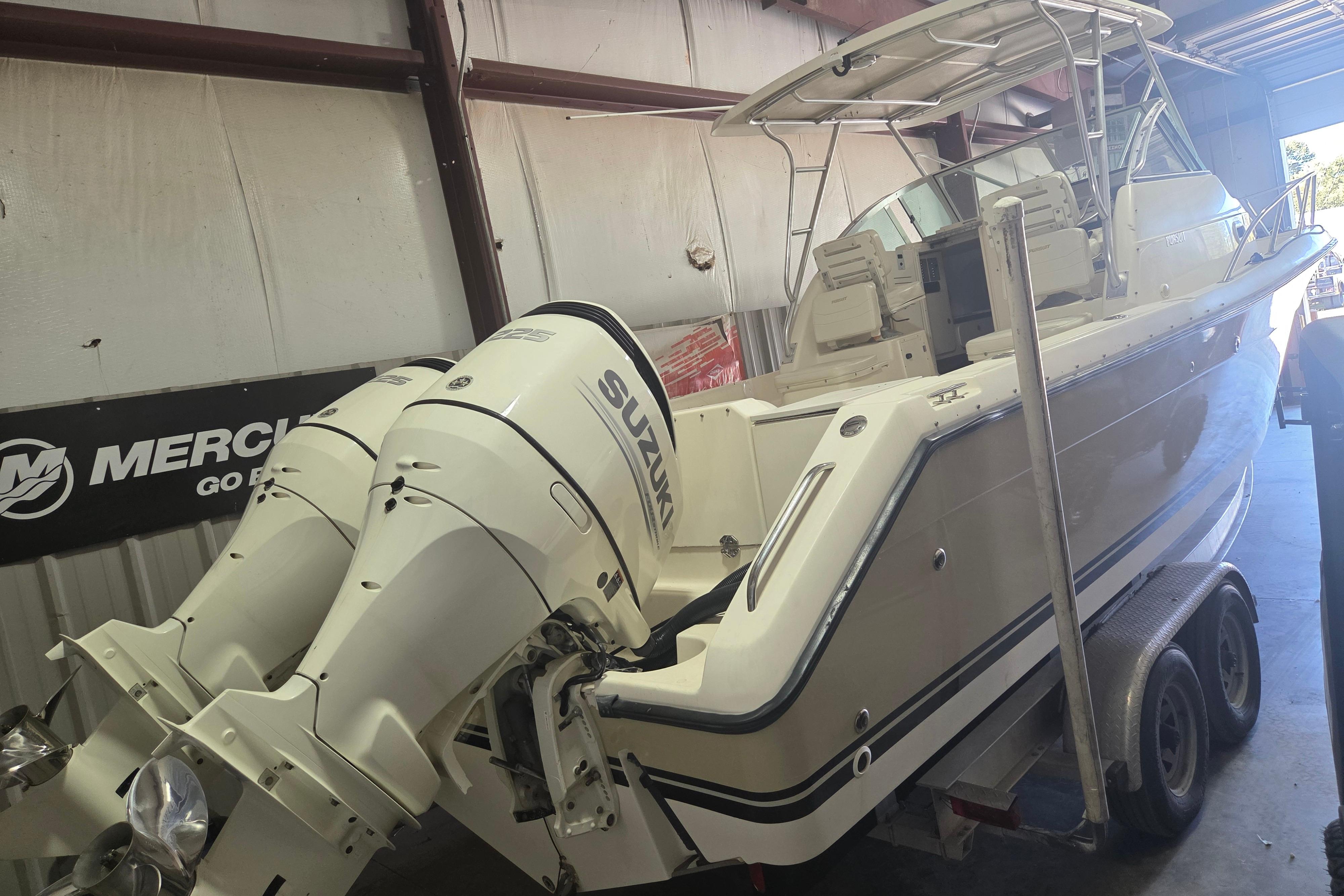 2001 Pursuit 2870 Walkaround boat with dual Suzuki outboard motors in a garage.