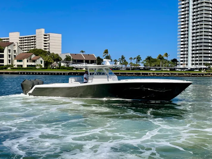 Caryali Yacht Photos Pics 2014 Invincible 42 Open Fisherman boat cruising near waterfront buildings.