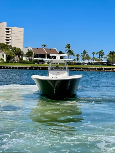 Caryali Yacht Photos Pics 2014 Invincible 42 Open Fisherman boat cruising on a sunny day near waterfront buildings.