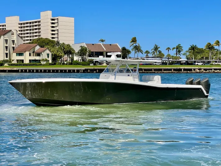 Caryali Yacht Photos Pics 2014 Invincible 42 Open Fisherman boat cruising on a sunny day near waterfront buildings.