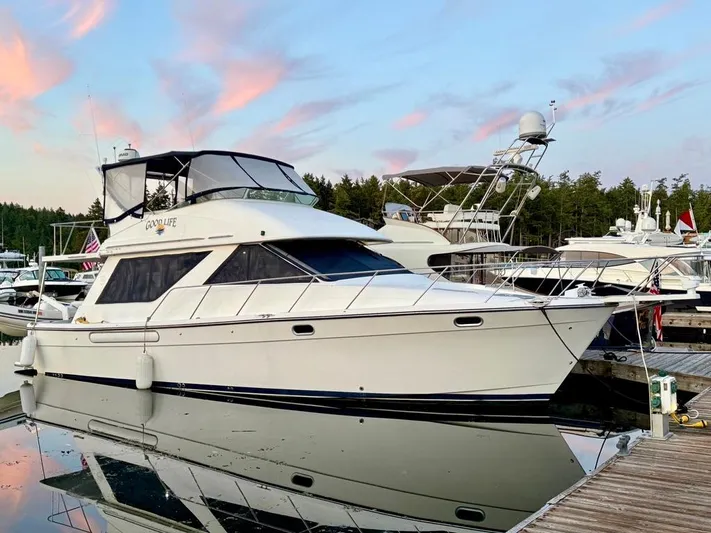  Yacht Photos Pics 2002 Bayliner 3988 yacht docked at marina, reflecting on calm water under a colorful sky.