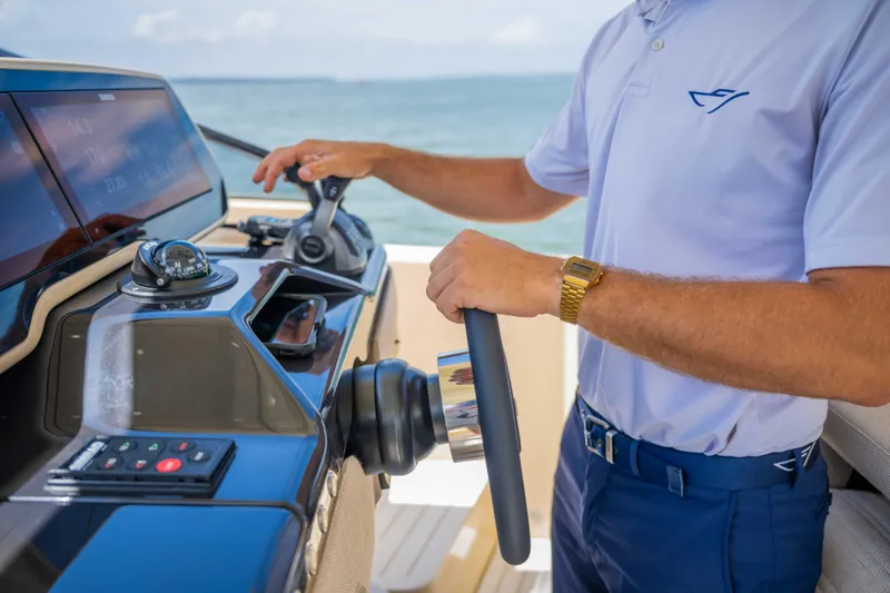  Yacht Photos Pics Person steering a 2026 Bellini Astor 36 yacht, showcasing modern controls and navigation.