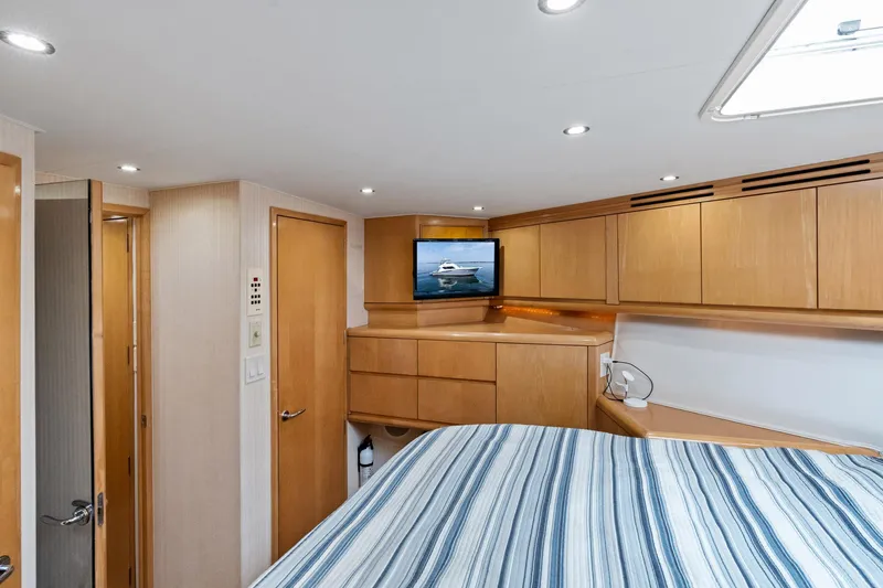 Amp'd Up Yacht Photos Pics Luxurious cabin interior of 1999 Hatteras 60 Convertible yacht with wood cabinetry and striped bedding.