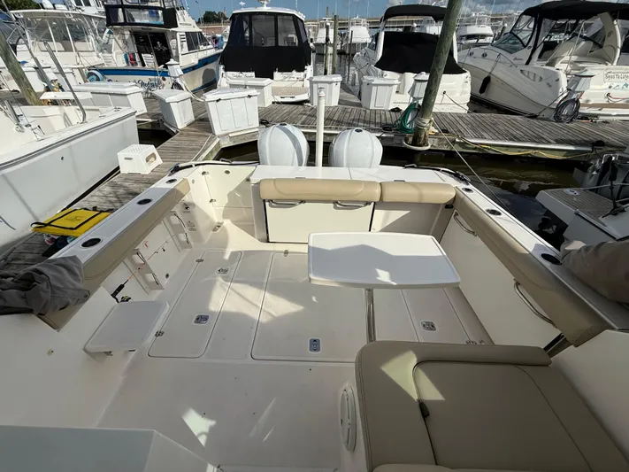  Yacht Photos Pics 2017 Pursuit DC 325 Dual Console boat interior at marina, featuring seating and table.
