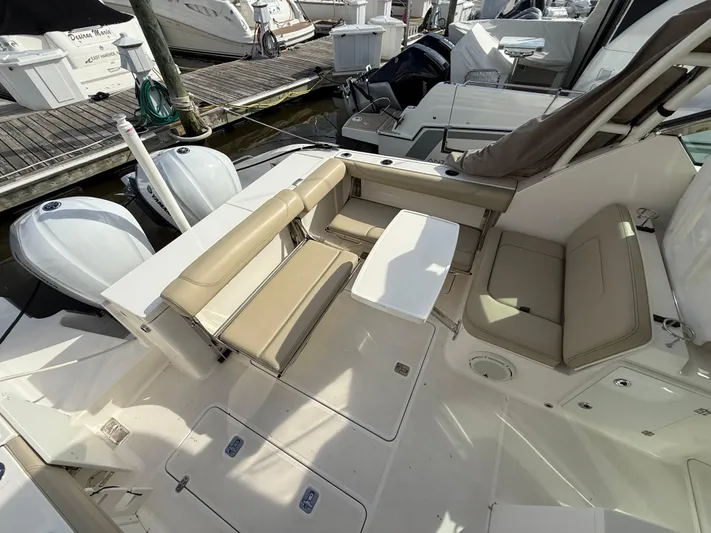  Yacht Photos Pics 2017 Pursuit DC 325 Dual Console boat interior with seating and table, docked at marina.