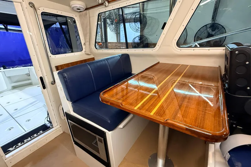 Kapalua Yacht Photos Pics Interior of 2013 Ocean Sport Roamer 33 with wooden table and blue seating.
