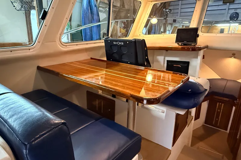Kapalua Yacht Photos Pics Interior of 2013 Ocean Sport Roamer 33 with polished wood table and blue seating.