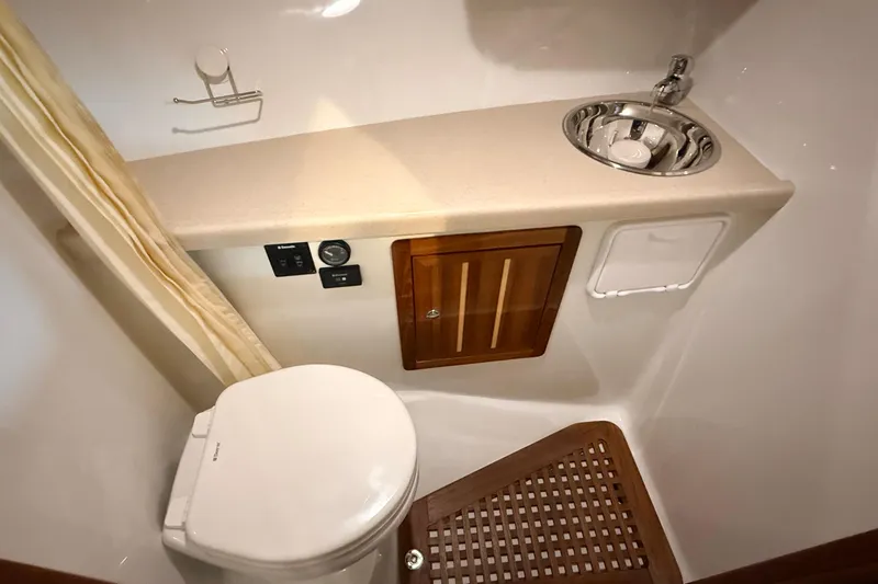 Kapalua Yacht Photos Pics Compact bathroom in 2013 Ocean Sport Roamer 33 with toilet, sink, and wooden accents.