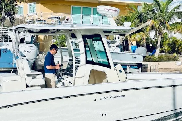  Yacht Photos Pics 2016 Boston Whaler 320 Outrage boat docked, with a person onboard, near a tropical setting.