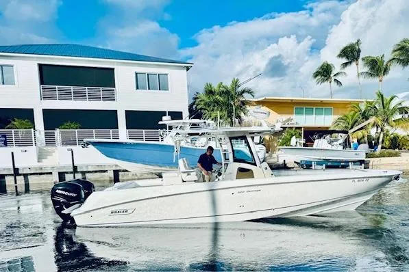  Yacht Photos Pics 2016 Boston Whaler 320 Outrage boat docked near waterfront homes with palm trees.