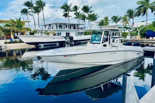  Yacht Photos Pics 2016 Boston Whaler 320 Outrage boat docked, surrounded by palm trees and waterfront homes.