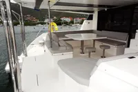 Leopard 50 yacht 2020 model, spacious outdoor seating area with table, docked near colorful buildings.