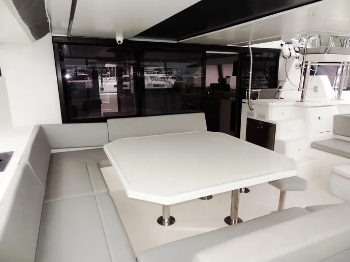Voila Yacht Photos Pics Modern dining area on a 2020 Leopard 50 yacht with white table and gray seating.