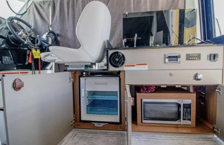  Yacht Photos Pics Interior of 2021 Beneteau Antares showing helm, mini fridge, and microwave setup.