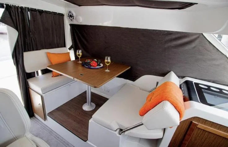  Yacht Photos Pics Interior of 2021 Beneteau Antares boat with dining area, table, and seating.
