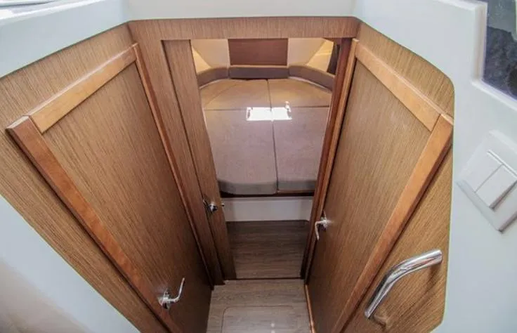 Yacht Photos Pics Interior cabin view of 2021 Beneteau Antares boat with wooden doors and cozy bed.