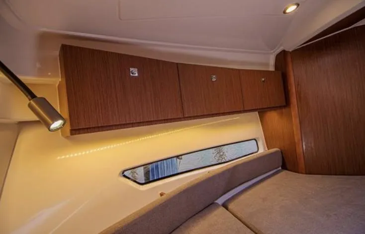  Yacht Photos Pics Interior cabin of 2021 Beneteau Antares boat with wooden cabinets and cozy seating.