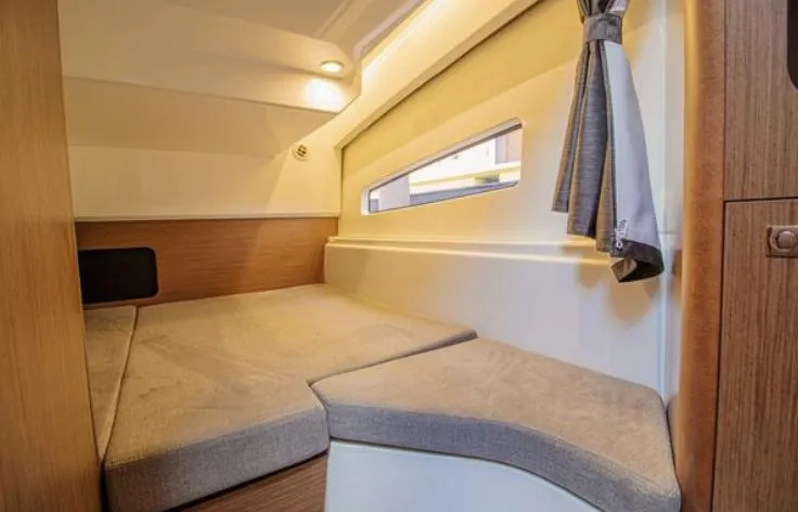  Yacht Photos Pics 2021 Beneteau Antares cabin interior with cozy bed and window view.