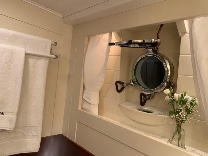 Iduna Yacht Photos Pics Classic 1939 Feadship yacht interior with porthole, white towels, and flowers.
