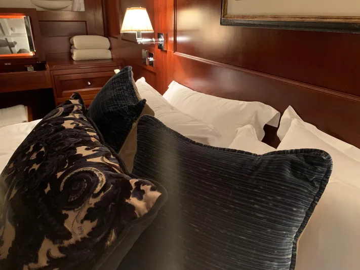 Iduna Yacht Photos Pics Luxurious cabin interior of 1939 Feadship Classic Sailing Yacht with plush pillows and warm lighting.
