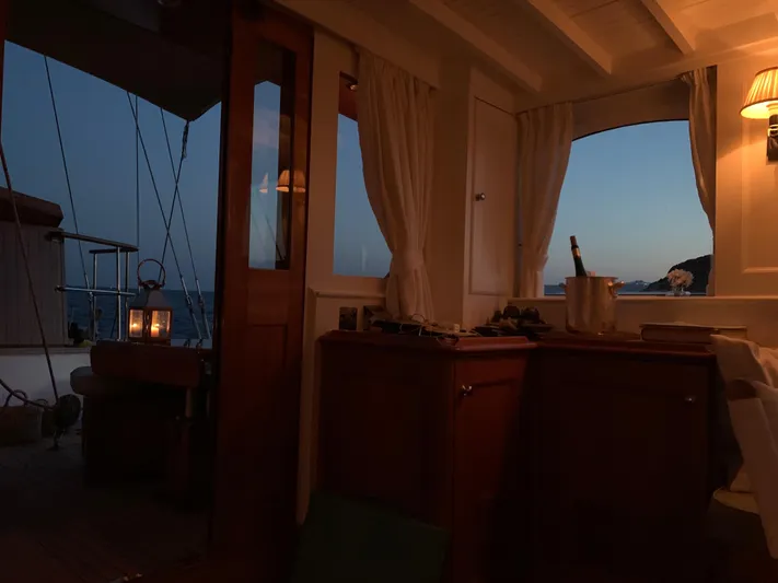 Iduna Yacht Photos Pics Classic 1939 Feadship sailing yacht interior at dusk, featuring elegant wooden cabinetry and soft lighting.