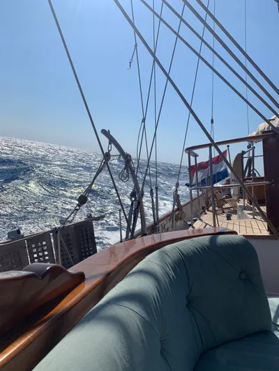 Iduna Yacht Photos Pics Classic 1939 Feadship sailing yacht on open sea with Dutch flag, sunny day.