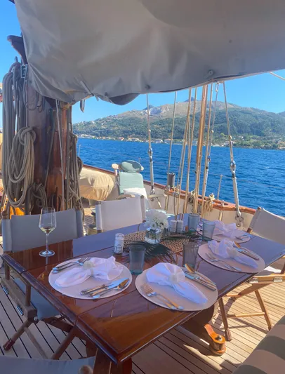 Iduna Yacht Photos Pics Elegant dining setup on 1939 Feadship Classic Sailing Yacht, overlooking serene blue waters.