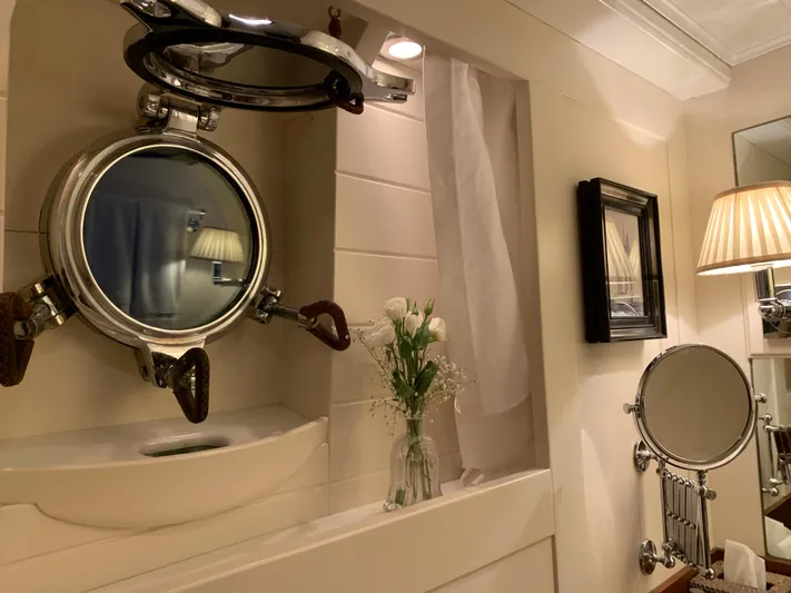 Iduna Yacht Photos Pics Classic 1939 Feadship yacht bathroom with porthole, elegant decor, and vintage lighting.