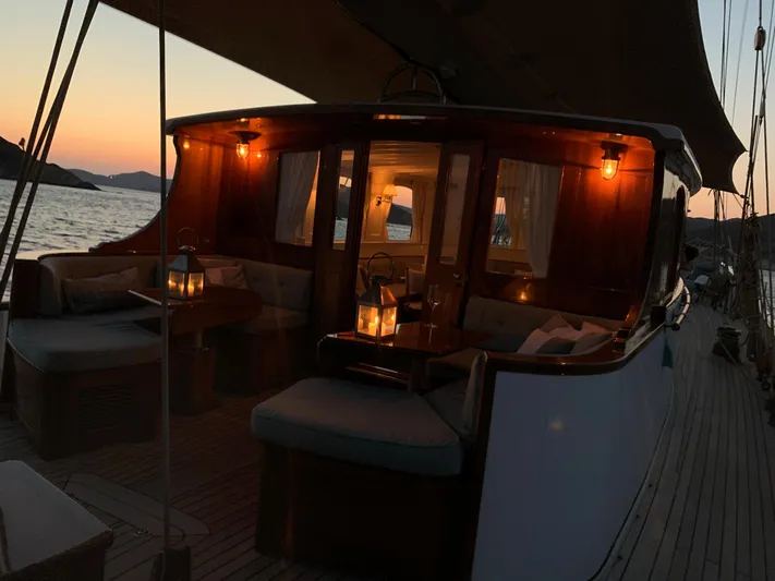 Iduna Yacht Photos Pics Classic 1939 Feadship sailing yacht at sunset, featuring elegant wooden interior and soft lighting.