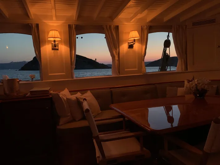 Iduna Yacht Photos Pics Interior of 1939 Feadship Classic Sailing Yacht at sunset, featuring elegant wooden decor and cozy seating.
