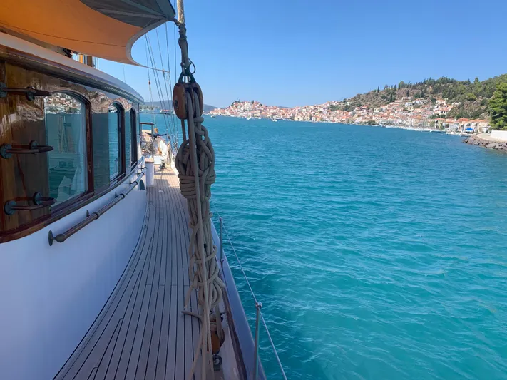 Iduna Yacht Photos Pics Classic 1939 Feadship sailing yacht on clear blue waters near a coastal town.