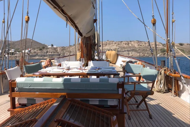 Iduna Yacht Photos Pics Classic 1939 Feadship sailing yacht deck with dining area and scenic coastal view.