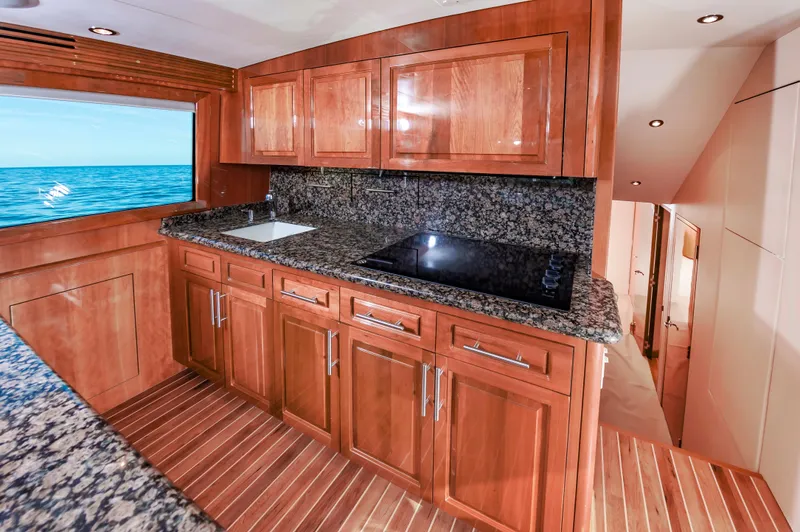 Sea Trader Yacht Photos Pics Luxurious kitchen in 2005 Hatteras 60 Convertible yacht with wood cabinetry and ocean view.
