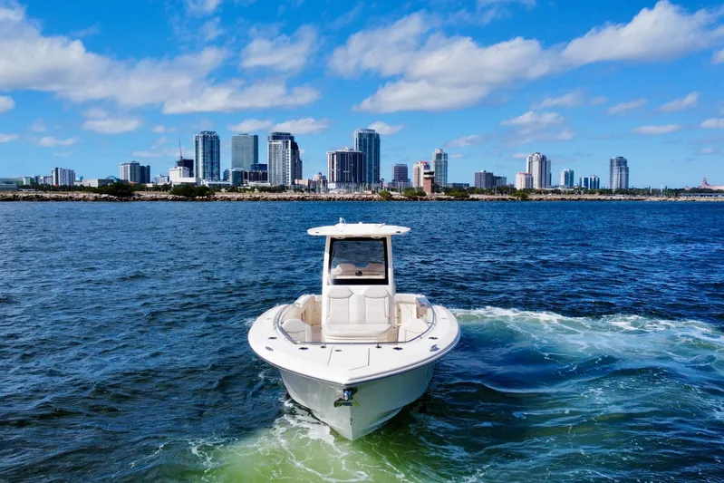  Yacht Photos Pics 2026 Scout 288 LXF boat cruising near city skyline on a sunny day.