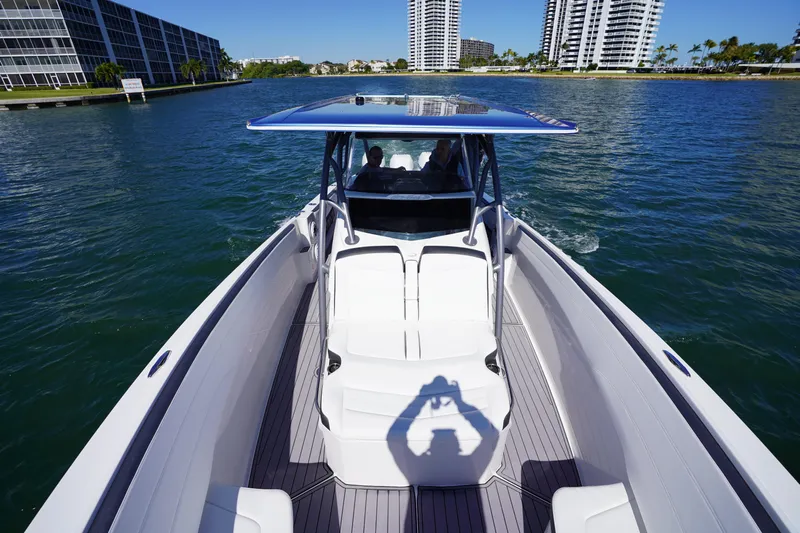  Yacht Photos Pics 2023 Nor-Tech 340 Sport Open Center Console cruising on a sunny day near waterfront buildings.