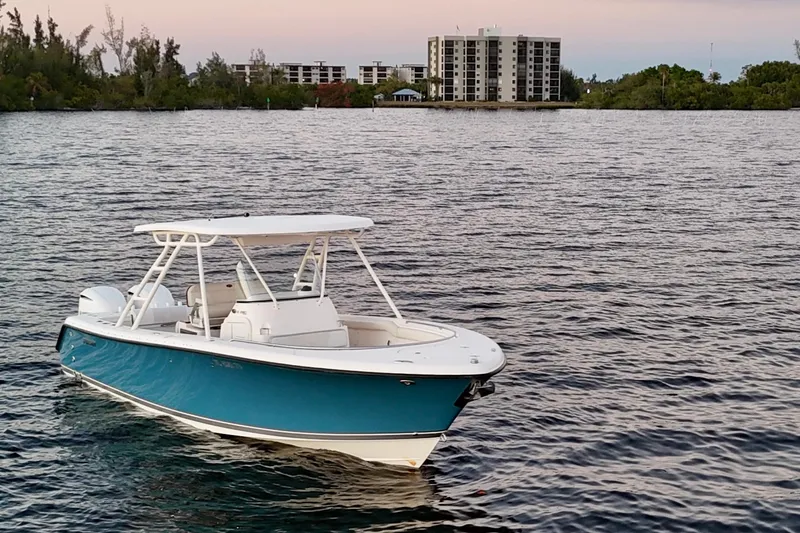  Yacht Photos Pics 2014 Pursuit S 280 Sport boat on calm water with buildings in the background.