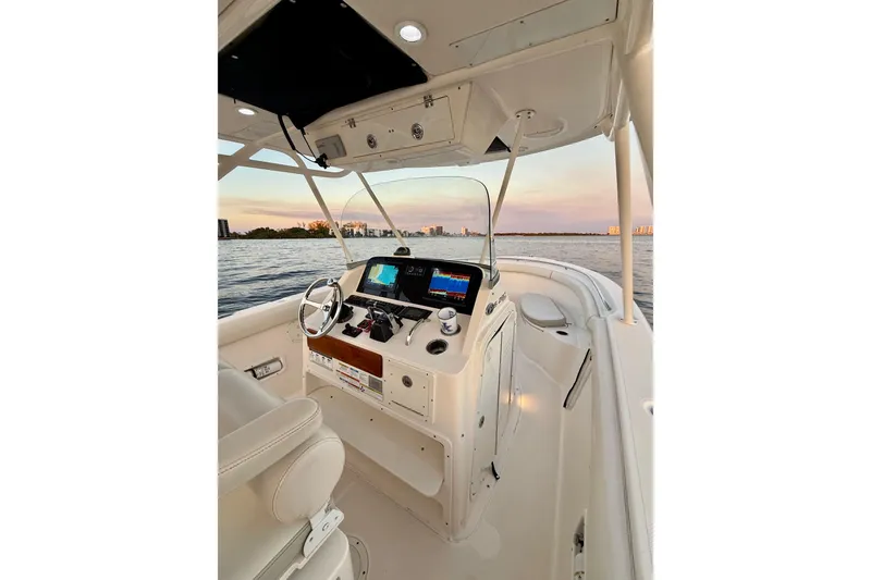  Yacht Photos Pics 2014 Pursuit S 280 Sport boat interior with steering console, on calm water at sunset.
