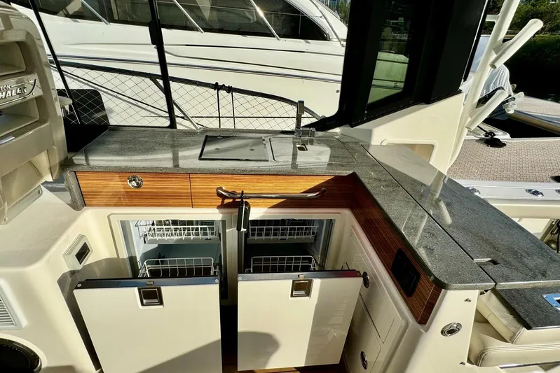 Days Ahead Yacht Photos Pics 2022 Boston Whaler 405 Conquest boat kitchen with granite countertop and storage cabinets.