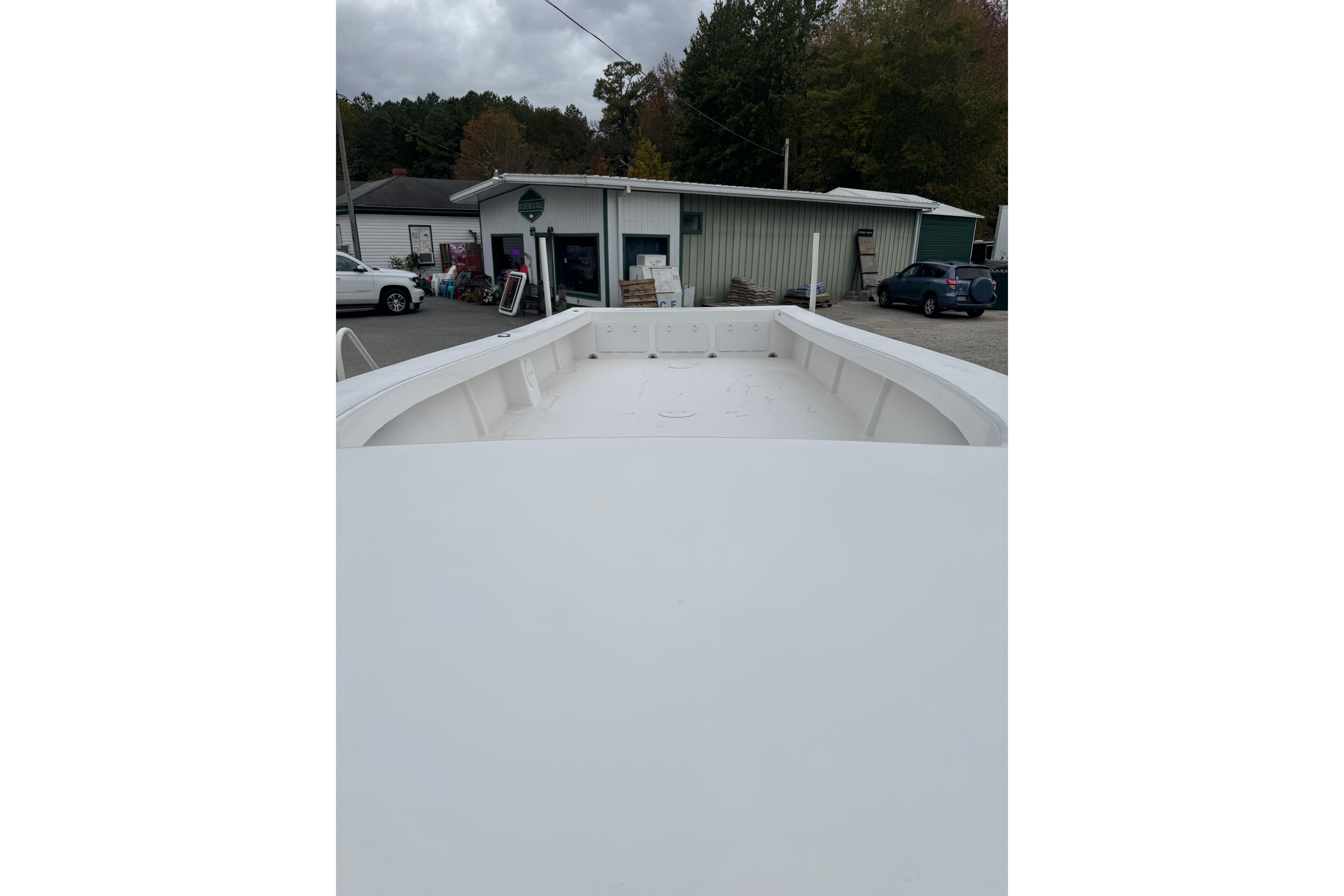 2026 C-Hawk 26 Center Console boat, white deck, parked near buildings and vehicles.
